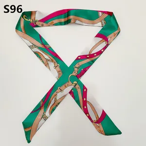 Detail of a green and rose pink satin twilly scarf with vintage belt and chain patterns