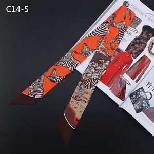 Detailweergave van een oranje satijnen Twilly-sjaal met zebraprint als tasaccessoire