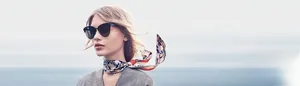 Detail view of a large black round cat-eye sunglasses and printed silk scarf for women