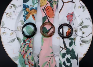 Close-up of resin scarf rings in black and amber marble finish on floral pattern