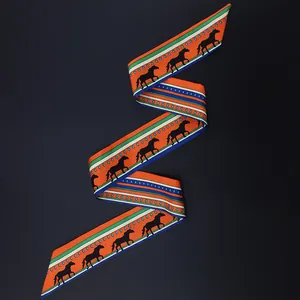 Macro shot of an orange twilly silk scarf with horse silhouettes and stripes