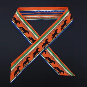 Detail of equestrian themed orange silk twilly scarf featuring black horse silhouettes
