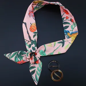 Pink floral silk scarf with dark brown and tortoiseshell resin rings on blue background