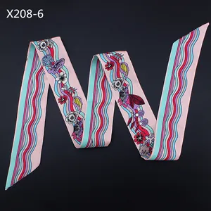 Détail du foulard en satin plié avec motifs floraux et vagues sur fond rose doux