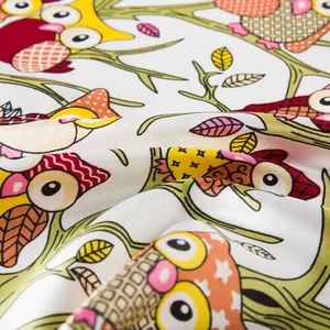 Macro detail of silk-like scarf fabric featuring colorful cartoon owl prints and patterns
