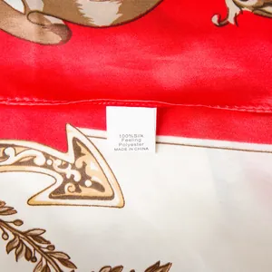Macro detail of the fabric care label on a red and beige printed silk-feeling scarf
