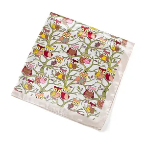 Close-up of square satin scarf with owl patterns and smooth champagne silk borders