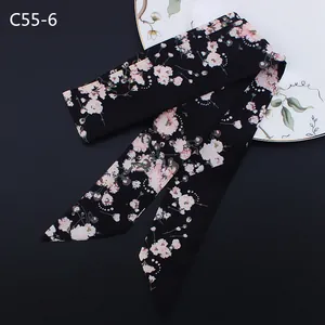 Detail of floral skinny scarf with pink flowers on black fabric over a ceramic plate