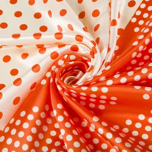 Silky 90x90cm scarf with vibrant orange and cream polka dots featuring glossy fabric texture