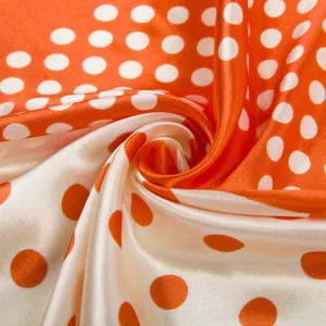 Detailed close-up showing the silky texture and elegant orange polka dot pattern fold