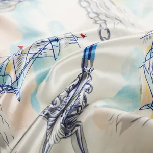 Dettaglio del foulard di seta piegato che mostra la trama satinata e la stampa nautica