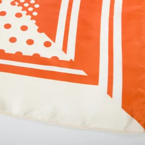 Macro shot of silk scarf showing orange and white geometric dots and smooth fabric texture