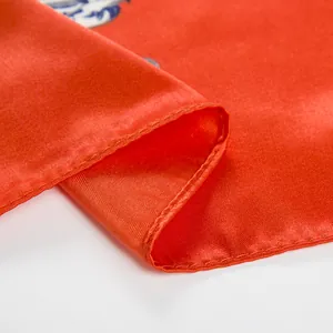Dettaglio ravvicinato di un foulard di seta rossa con rifinitura artigianale dei bordi