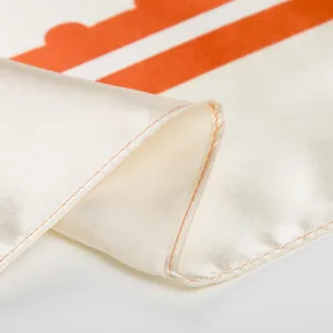 Detail of silk satin scarf showing orange rolled hem and wavy geometric patterns