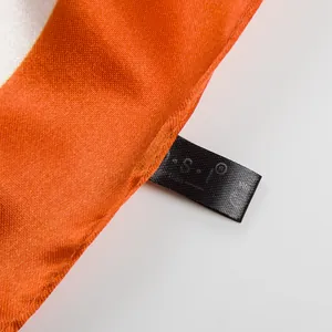 Macro detail of high-quality orange and white satin scarf fabric with fine stitching