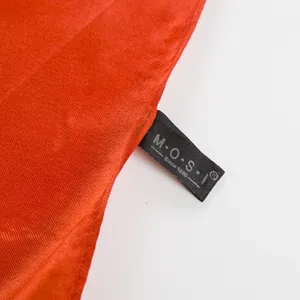 Dettaglio macro dello scialle di seta rossa con etichetta nera e trama fine