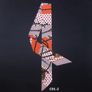 French style twilly silk scarf with orange polka dots and gold chain pattern on grey backdrop