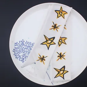 Pañuelo twilly de seda blanca con estrellas amarillas pintadas a mano en un plato cerámico