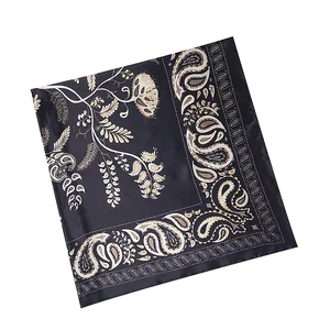 Detail of black silk scarf featuring beige paisley patterns and floral scrollwork