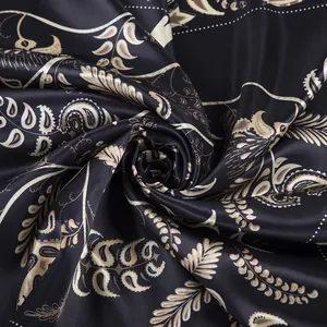 Macro detail of the spiral folded silk scarf showing paisley patterns and satin luster