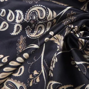 Detail of bohemian paisley pattern on black satin silk scarf with elegant drape and luster