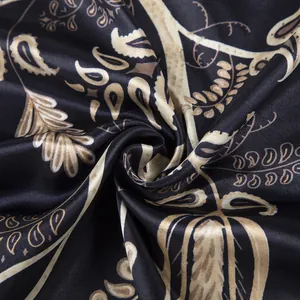 Detailed close-up of bohemian paisley silk scarf featuring gold patterns on black fabric