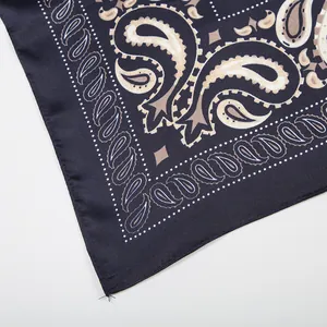 Detail of silk-like navy scarf showing classic paisley pattern and neat hemmed edges