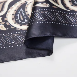 Detailed close-up of bohemian paisley pattern and white polka dot edge on blue silk scarf
