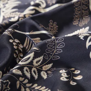 Macro shot of dark blue silk scarf with beige paisley and botanical leaf patterns