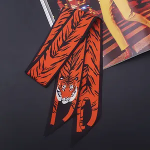 Gros plan détaillé d'un foulard en soie à imprimé tigre avec des tons orange vif sur l'anse