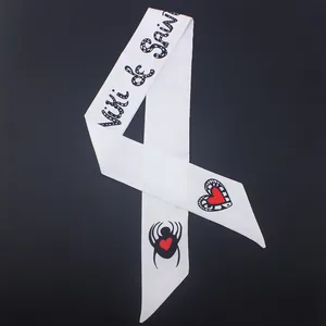Macro shot of white silk ribbon scarf with spider heart print and artistic lettering