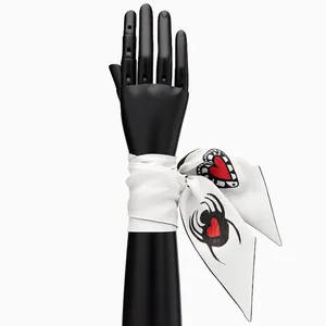 White silk scarf with black spider and red heart patterns shown on a mannequin hand