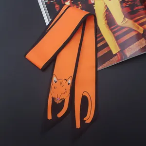Détail d'un foulard en soie orange avec liseré noir et motif de chat de dessin animé