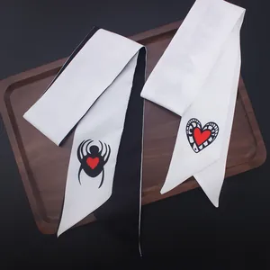 Detail of silk twilly scarves with spider and heart patterns on a wooden tray