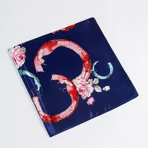 Close-up of silk-feel square scarf featuring red abstract circles and pink roses patterns