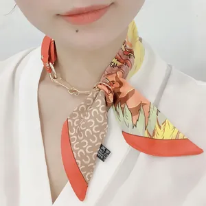 Gros plan d'un foulard en soie orange tissé dans une chaîne dorée sur un mannequin
