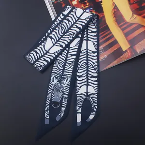 Vue détaillée d'un foulard étroit en soie à motif zébré noué sur une poignée de sac