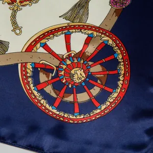 Detailed close-up of navy silk scarf featuring ornate carriage wheels and gold tassels