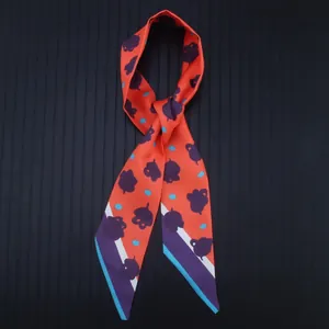 Orange silk-like twilly scarf with purple leaf patterns and striped edges for bags or hair