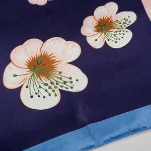 Macro-opname van blauwe zijden sjaal met roze bloemenprint en fijne afgewerkte zoom