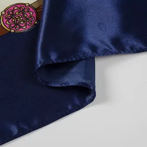 Close-up of a navy blue satin silk scarf showing fine texture and hemmed edge details