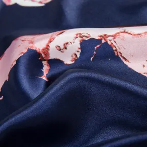 Macro detail of navy silk scarf fabric featuring smooth texture and pink floral patterns