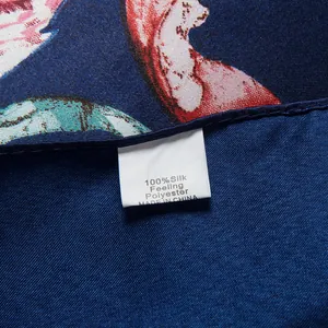 Close-up of silk-feel scarf label showing 100% polyester fabric and rolled hem details
