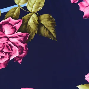 Macro detail of silk-like scarf fabric with pink roses and green leaves on navy base