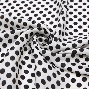 Détail du foulard en soie à pois noirs et blancs montrant le drapé fluide du tissu