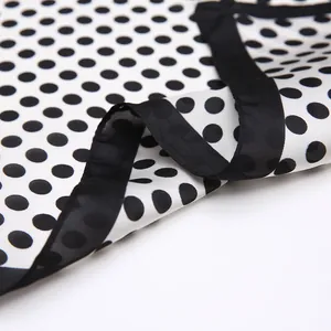 Détail d'un foulard en soie à pois avec texture satinée et bordure noire cousue