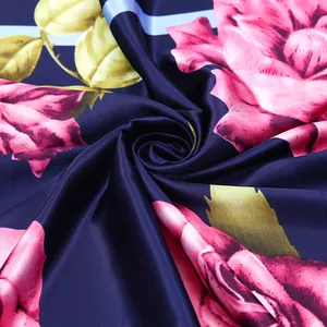 Detailed shot of silk scarf fabric showing pink roses and golden leaves on blue