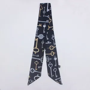 Detalle de un pañuelo twilly negro con motivos de llaves vintage y puntas en pico