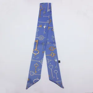 Detalle del pañuelo twilly azul con elegantes estampados de llaves vintage oro y plata