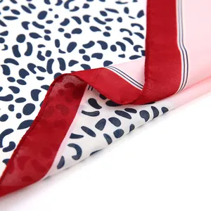 Close-up of leopard print silk scarf with red border and detailed rolled edge finish